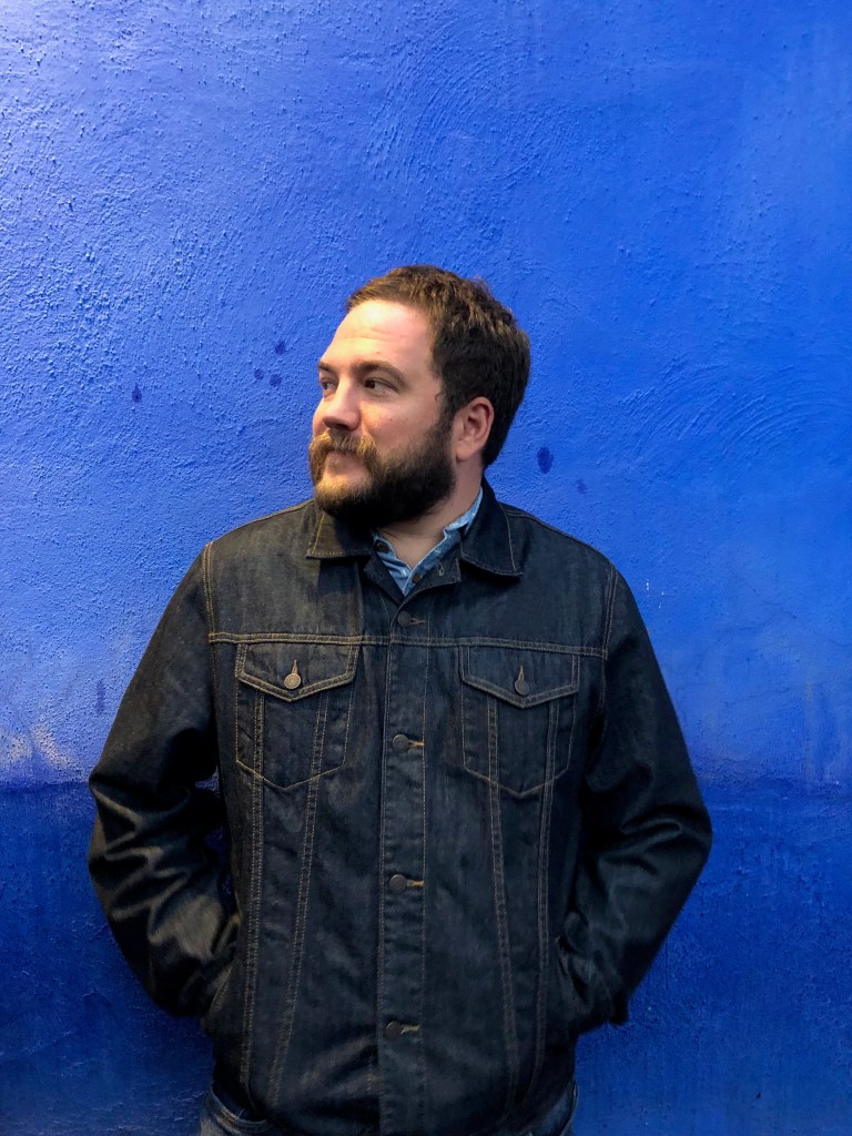 Terry Fagan in a denim jacket against a concrete wall.